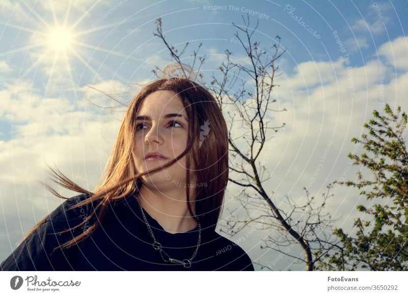 Mädchen steht im Freien mit blauem Himmel, Baum und Sonne Porträt Natur Person Tag Schönheit modern attraktiv wirklich echte Person Behaarung Textfreiraum