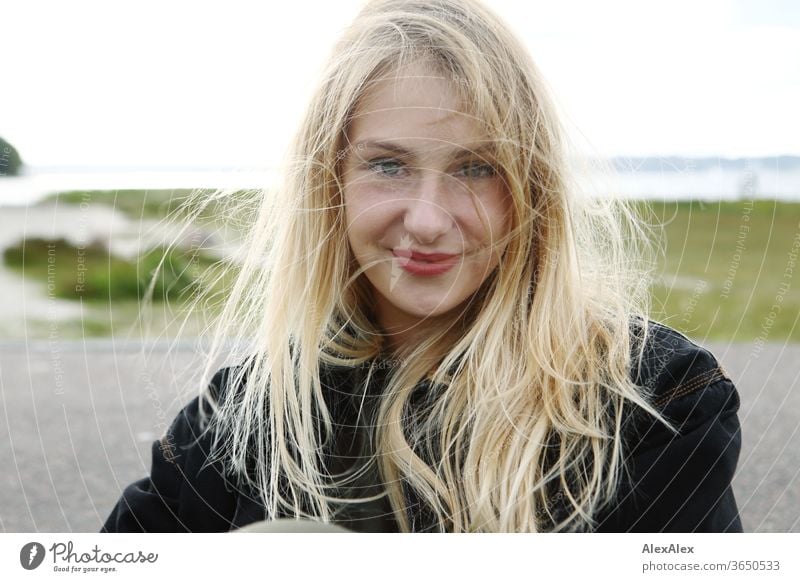 Gegenlicht Portrait einer jungen, blonden, lächelnden Frau am Meer junge Frau schön schlank langhaarig windig ästhetisch Sommer Ausflug Schönes Wetter Model