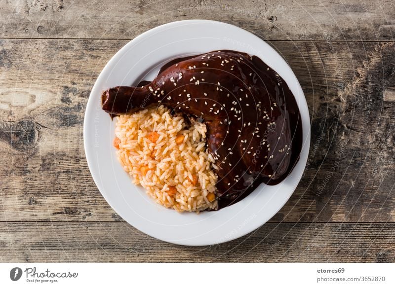 Traditioneller Maulwurf Poblano mit Reis im Teller auf Holztisch. Ansicht von oben Hähnchen Hühner-Maulwurf Peperoni chipotle Schokolade Zimt Mais lecker Speise