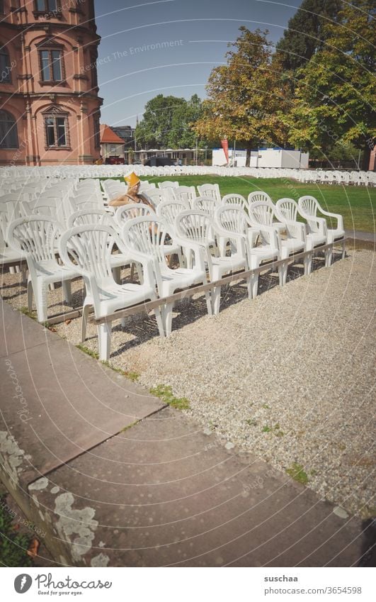 jugendliche sitzt auf einer zwecks vorstellung bestuhlten außenfläche und hat einen popcornbecher auf dem kopf Unsinn machen Blödsinn Jugend Pubertät