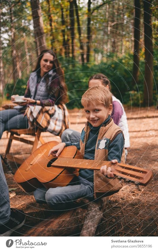 Glückliche Familie auf einem Campingausflug zur Entspannung im Herbstwald. Ein Junge hält eine Gitarre in den Händen fallen Natur Vater Mutter Zusammensein Spaß