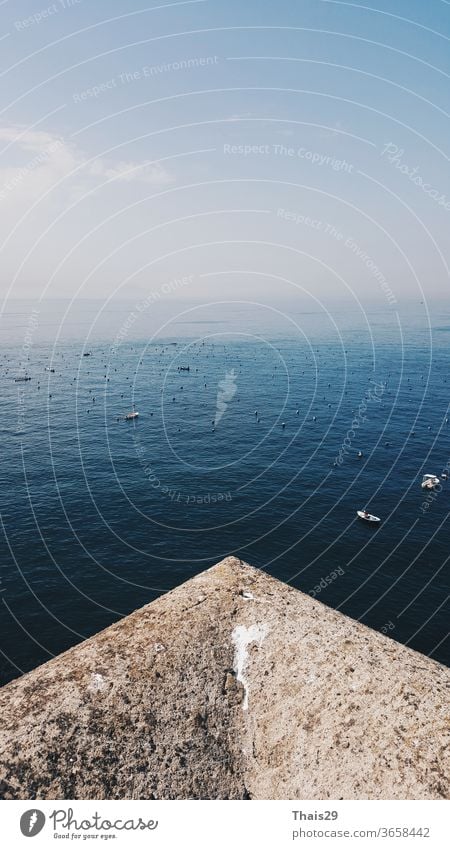 Hochseeansicht Landschaft Horizont Perspektive von der Steinmauer auf das blaue Meer, sauberer Himmel und ruhiges Wasser mit kleinen Booten, Italien, Mailand