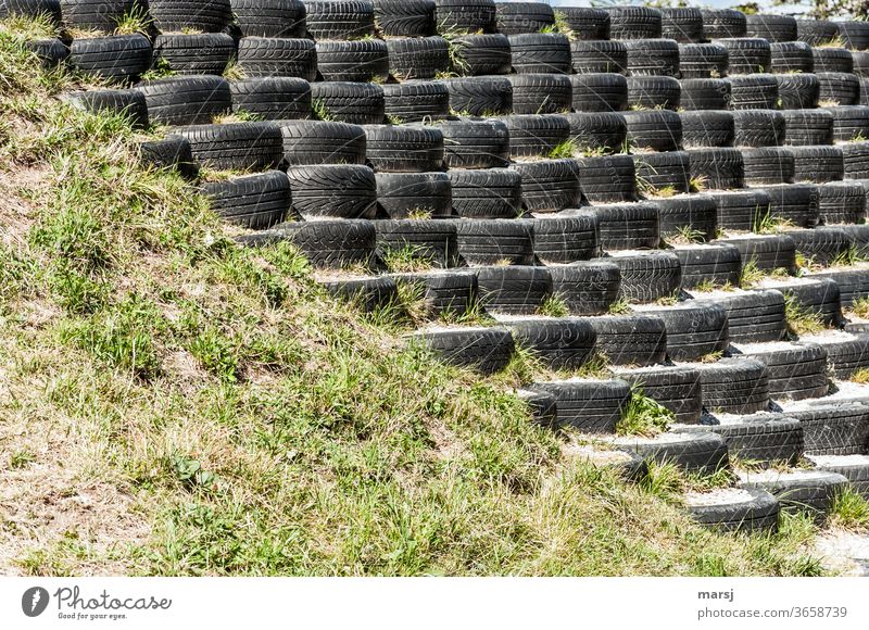 Alt-Autoreifensammlung mit wenig Profil, stufenförmig aufgebaut und diagonal geteilt mit Wiese Altreifen Stufen Treppe aufwärts Farbfoto Abstieg abwärts