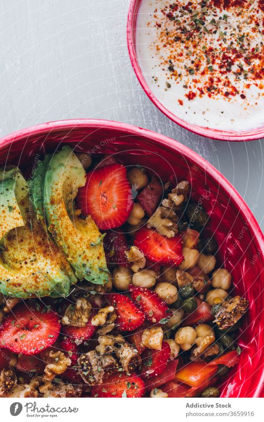 Nutzpflanzenfrau mit Schüssel mit frischem, köstlichem Bio-Kichererbsensalat Frau lecker Salatbeilage Avocado Erdbeeren Walnussholz Saucen organisch Gesundheit