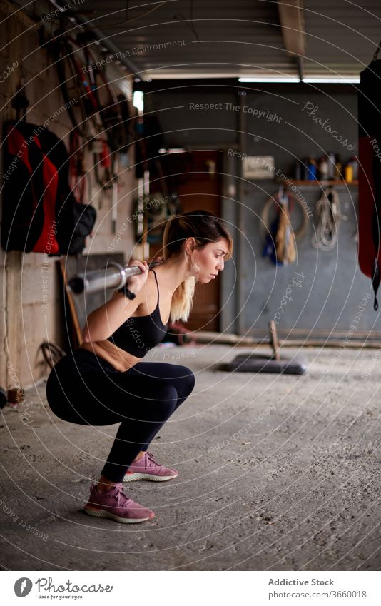 Schlanke Sportlerin beim Training mit Langhantel im Fitnessstudio Curl-Hantel Übung Konzentration passen Gerät sportlich Fokus Körper Sportkleidung stark