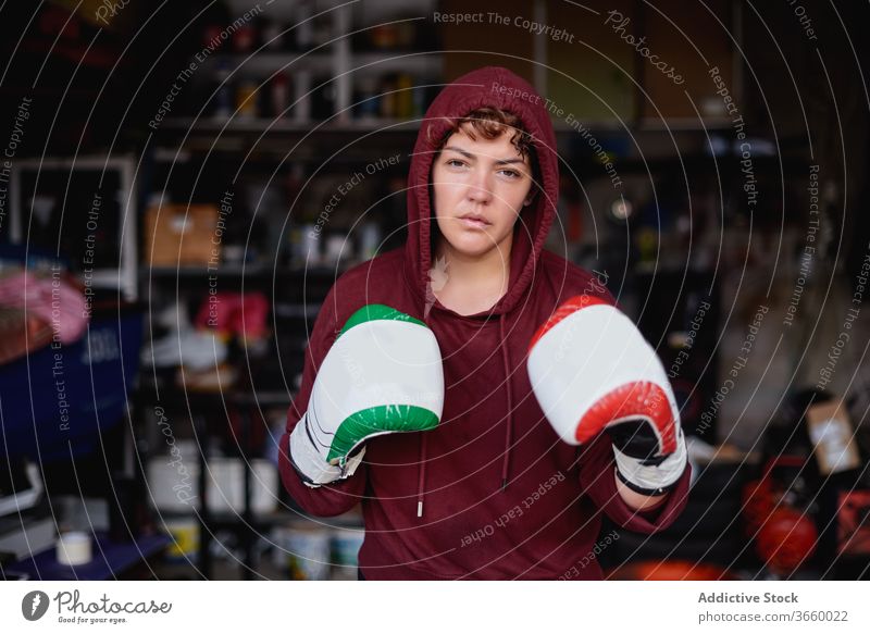 Entschlossene Sportlerin beim Schattenboxen im Fitnessstudio Boxer Boxsport Handschuh Bowle ernst Bestimmen Sie Training Garage stark Konzentration passen