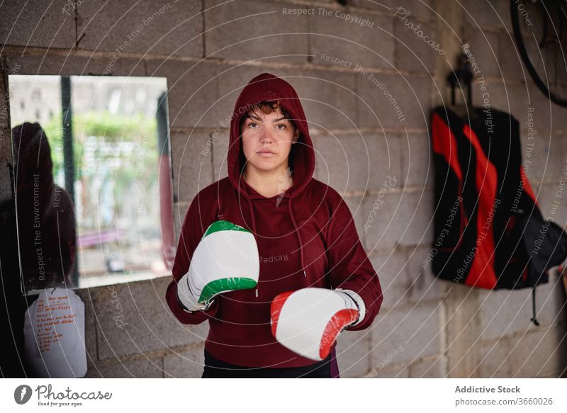 Entschlossene Sportlerin beim Schattenboxen im Fitnessstudio Boxer Boxsport Handschuh Bowle ernst Bestimmen Sie Training Garage stark Konzentration passen