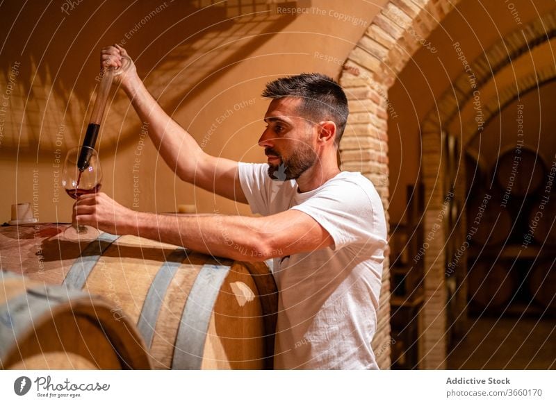 Professioneller Winzer gießt Wein in Glas mit speziellem Glaswerkzeug eingießen Werkzeug Verkostung Lauf Rotwein Weingut ernst professionell Alkohol Fokus