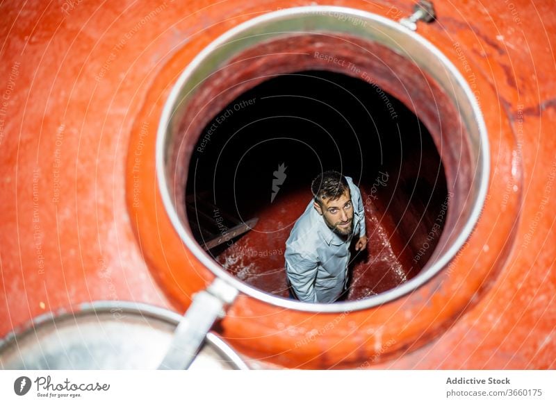 Inhaltswinzer auf der Treppe, die in den Weingärtank führt Winzer Fermentation Tank Laufmasche nach unten gehen Fabrik Beruf Inszenierung industriell