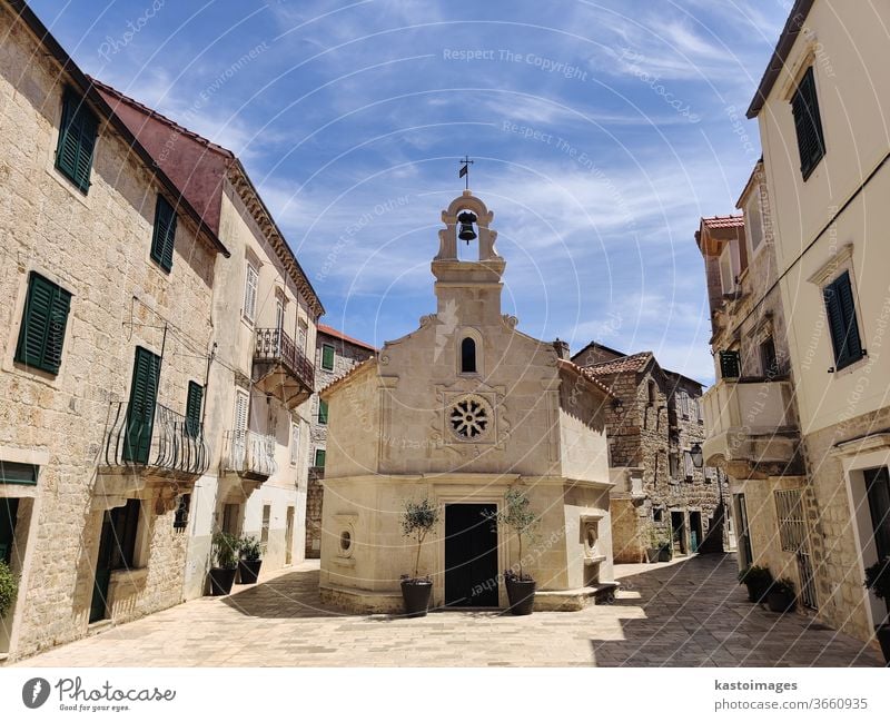 Malerisches altes, aus Stein gemeißeltes Kirchlein in der Mitte des traditionellen Stadtplatzes in Jelsa, Insel Hvar, Kroatien. Dorf Außenaufnahme Fischerdorf