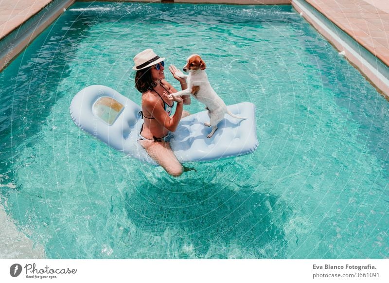 glückliche Frau und Hund in einem Pool, die Spaß haben. Hund sitzt auf einem Schlauchboot und spielt mit seinem Besitzer. Sommerzeit Schwimmbad aufblasbar