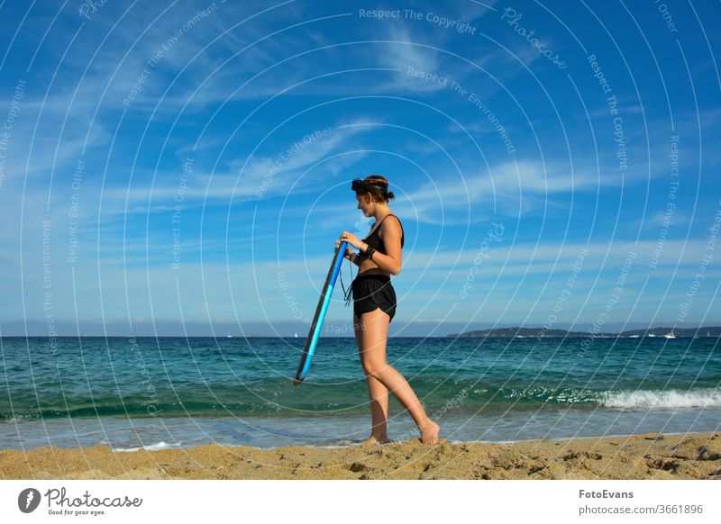 Junges Mädchen steht mit einem Schwimmbrett am Strand, im Hintergrund die Küste der Côte d'Azur natürlich Tribüne Natur Wasser Tag Sommer Holzplatte Kind