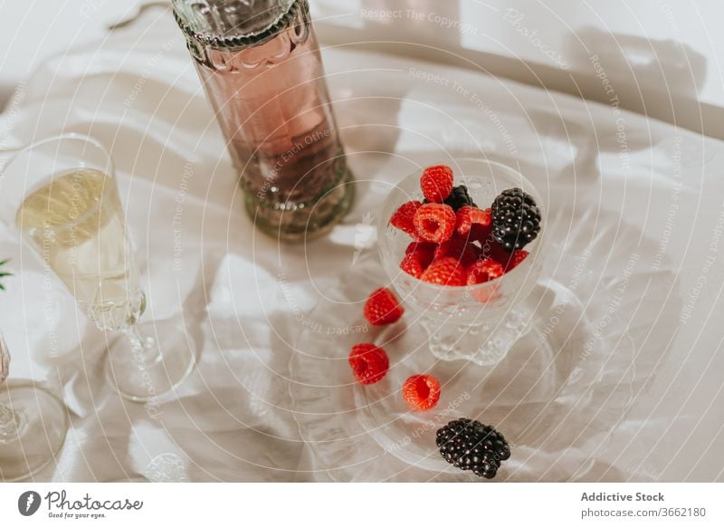 Glas Cocktail mit Beeren und Gläsern, serviert auf einem Tisch vor weißer Wand Flasche Teller trinken Zusammensetzung dienen Dekoration & Verzierung Design