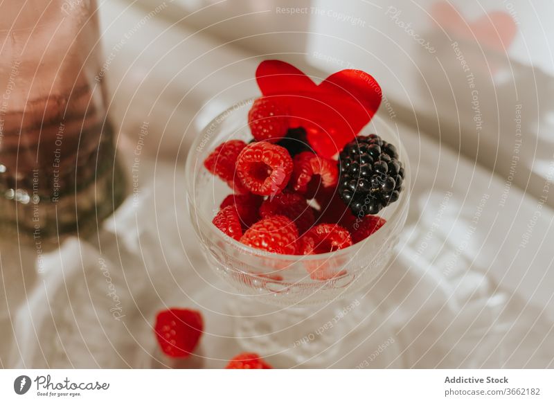 Glas Cocktail mit Beeren und Gläsern, serviert auf einem Tisch vor weißer Wand Flasche Teller trinken Zusammensetzung dienen Dekoration & Verzierung Design