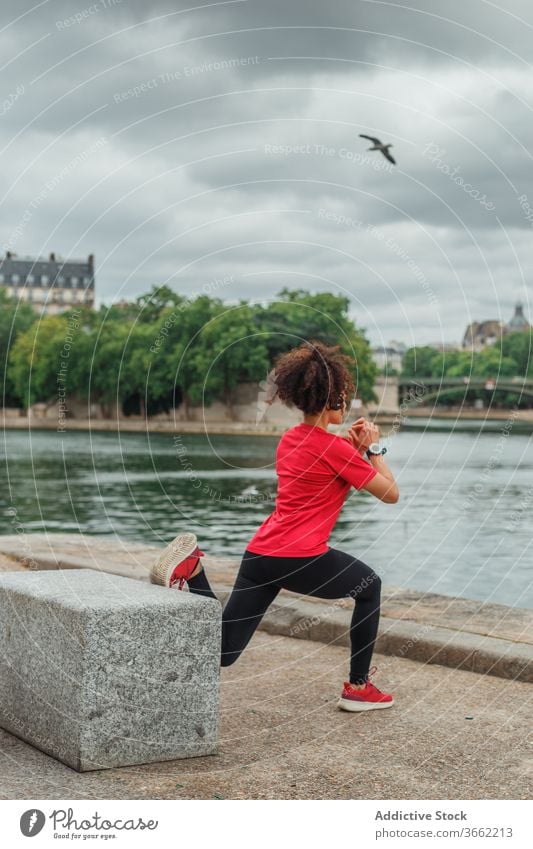 Nicht erkennbare Sportlerin, die während des Trainings in der Nähe des Stadtflusses die Beine streckt Dehnung Übung Sportkleidung Fluss Stauanlage