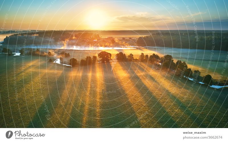 Erste Sonnenstrahlen über grünen Wiesen und Feldern. Sonniges sommerlich ruhiges Morgenpanorama. Nebel Fluss Natur Landschaft Sonnenaufgang Cloud Baum