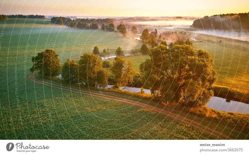 Sonniger Sommer-Nebelmorgen. Erste Sonnenstrahlen über grüner Wiese und Feld Fluss Morgen Natur Landschaft Sonnenaufgang Cloud Baum Hintergrund Umwelt Panorama