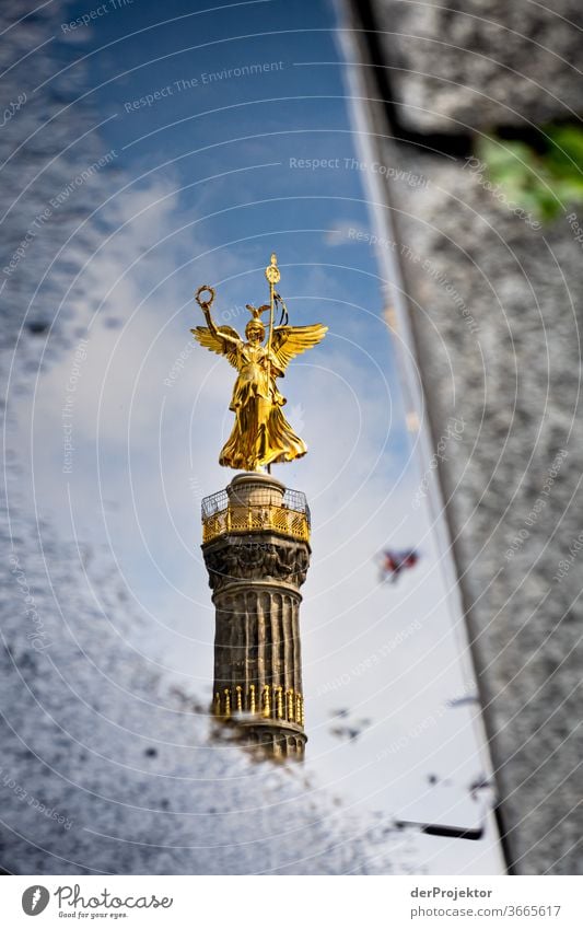 Siegessäule in einer Pfützenspiegelung mit Asphalt und Bordsteinkante Stadtzentrum Menschenleer Sehenswürdigkeit Wahrzeichen Denkmal Gold Statue Farbfoto