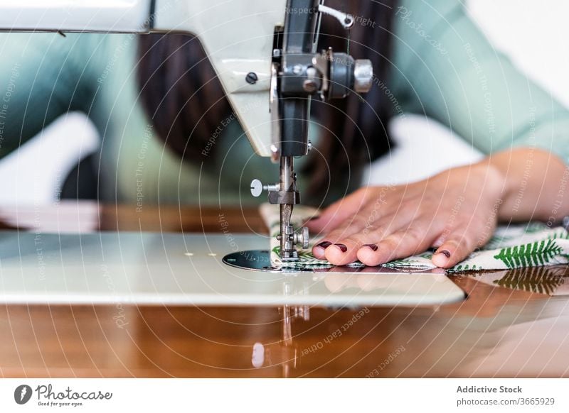 Schneidernähen auf einer Maschine in der Nähe einer Ziegelwand im Atelier Nähmaschine Basteln Probe Muster Lampe Kleinunternehmen Backsteinwand Werkstatt Gewebe