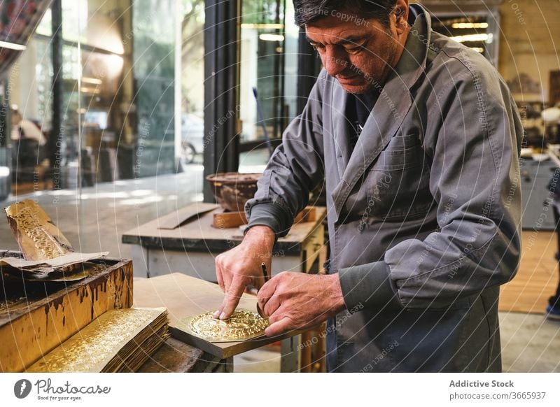 Reifer Juwelier, der im Workshop mit einem Bleistift Goldgegenstände herstellt Arbeit gold Metall Werkzeug Prozess Basteln konzentriert Kleinunternehmen