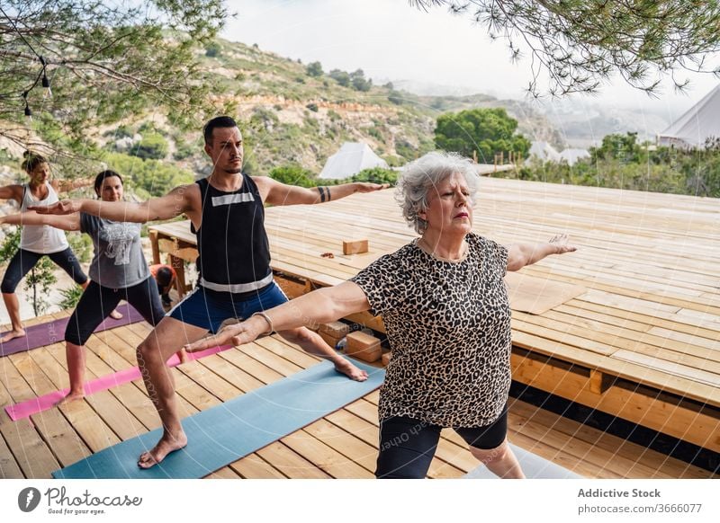 Team von aktiven Menschen, die im Camp eine Warrior-II-Yoga-Asana machen krieger ii virabhadrasana b Dehnung Wellness Gesundheit Gleichgewicht Lager Klasse üben