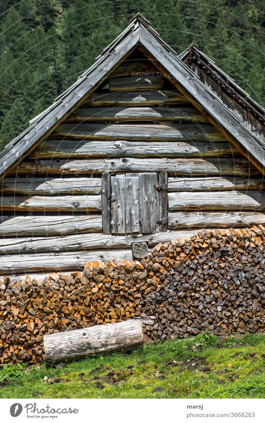 Genügend Holz vor der Hütte mit dem geschlossenen Fenster co2 CO2-neutral Brennholz geschlossenes Fenster gestapelt braun Holzstapel Brennstoff Stapel