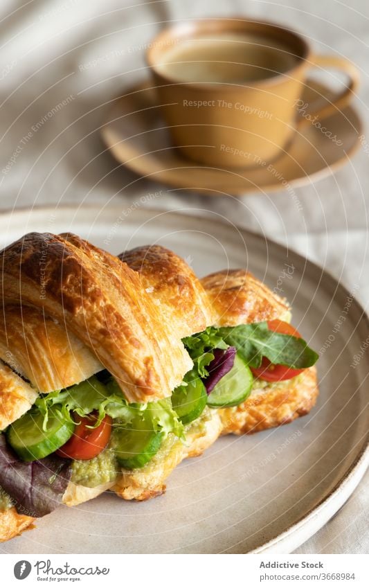 Köstliches veganes Sandwich auf Teller Veganer Frühstück Belegtes Brot Gemüse Morgen lecker frisch geschmackvoll Snack Vegetarier Salat Tisch Tasse Kaffee