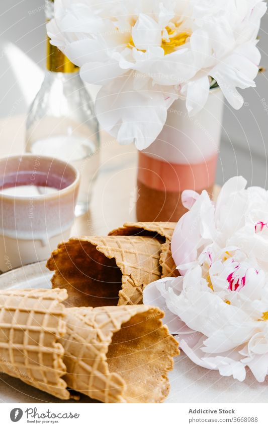 Köstliche Waffeltüten mit Blumen auf dem Tisch Zapfen geschmackvoll Knusprig Pfingstrose knirschen lecker hölzern Lebensmittel süß Dessert Tablett Feinschmecker