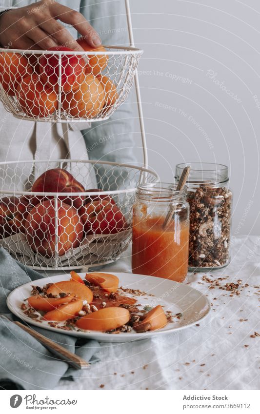 Crop-Person am Tisch während des Frühstücks Gesundheit Müsli Morgen Schalen & Schüsseln Frucht organisch Joghurt Lebensmittel frisch natürlich Vitamin lecker