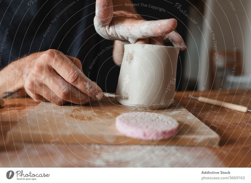 Crop männlich Keramiker schaffen Tasse Ton Kunstgewerbler Mann kreieren Herstellerin Fähigkeit Bürste Kunsthandwerker Werkstatt Handwerk professionell Hobby