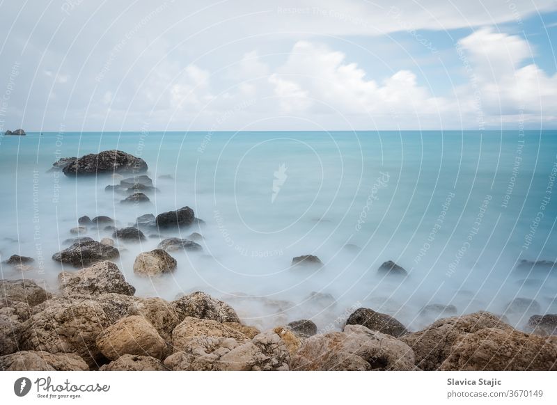 Langzeitbelichtungsbild eines Felsstrands vor einem Sturm Hintergrund Bucht Strand blau Windstille Küste Küstenlinie nach unten Abenddämmerung Belichtung