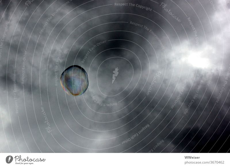 Seifenblase vor einem düster bewölkten Himmel Wolken Gewitter Regen Sturm Widerstand schillern Regenbogen fliegen schweben Luft einsam allein mutig Innenleben