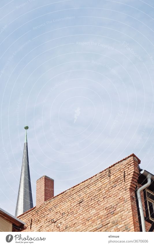 hinter dem Ziegelbaugebäude mit Schornstein ist eine Kirchturmspitze zu erkennen Gebäude wohnen Religion & Glaube Architektur Bauwerk Kirche Stadt Kleinstadt