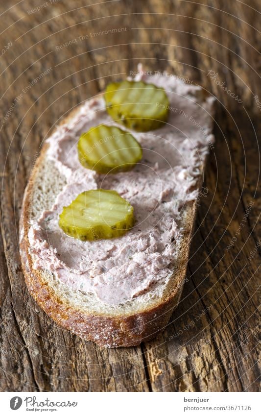 Leberwurstbrot auf dunklem Holz Snack Fleisch Pastete Stück Leberpastete Brot Vollkornbrot Fleischprodukt Wurst traditionell Schweinefleisch Oberansicht Brett