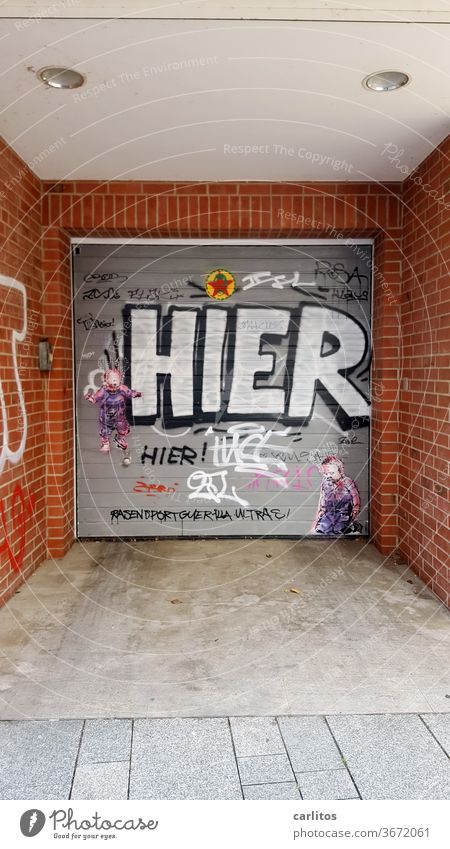 HIER ! Nur damit das klar ist ...... Einfahrt Tor Rolltor Graffiti Schmiererei Garage Garagentor geschlossen Gebäude Wand grau Innenstadt