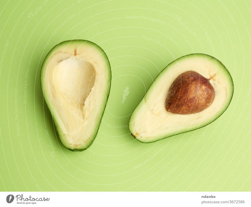 halbreife grüne Avocado mit braunem Kern auf grünem Hintergrund Ausschnitt Nahaufnahme Farbe Essen zubereiten Kerngehäuse geschnitten lecker Diät exotisch