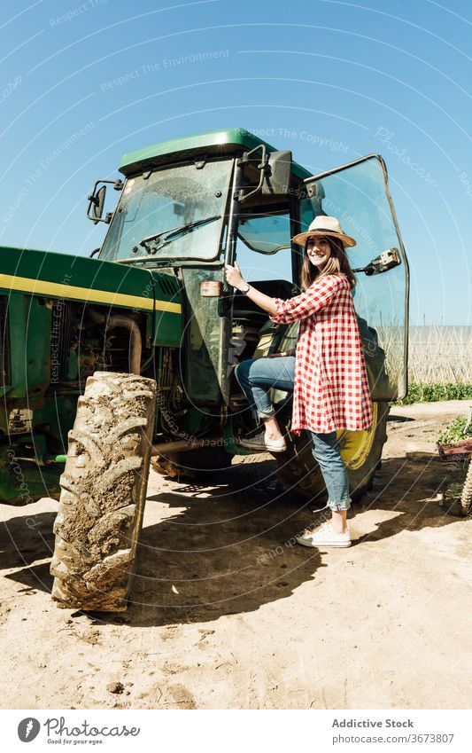 Fröhliche Frau steigt auf alten Traktor unter blauem Himmel weiterkommen positiv sandig Gelände Blauer Himmel Sommer Landschaft stehen idyllisch Harmonie