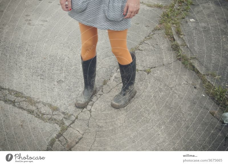 Nagellack und Gummistiefel Beine Mädchen dreckig gelbe Strümpfe Rock Straße stehen Rocktaschen Matschfestival Tristesse einsam warten junges Mädchen Kleid