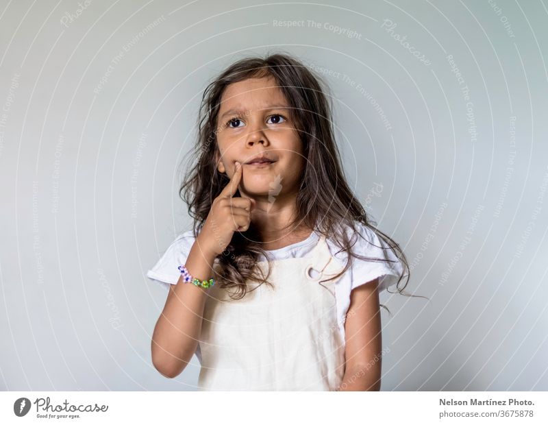 Nachdenkliches kleines Mädchen in ihrem Schlafzimmer. Sie ist nachdenklich und verwirrt. Lernen Schule Konzentration wenig Idee nachdenkend lernen hispanisch