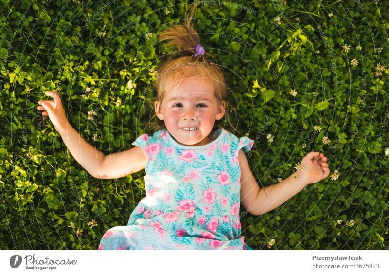 Hübsches kleines Mädchen liegt lachend im Gras und schaut auf. Baby Kindheit 2-3 happines bezaubernd niedlich Natur Lachender Spaß Gefühle Lächeln