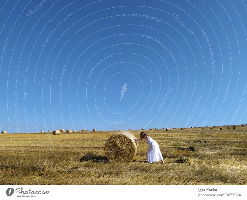 Frau schiebt Heuballen auf dem Feld drücken rollierend Himmel Sonnenlicht malerisch Ackerbau Bauernhof Ernte ländlich Sommer