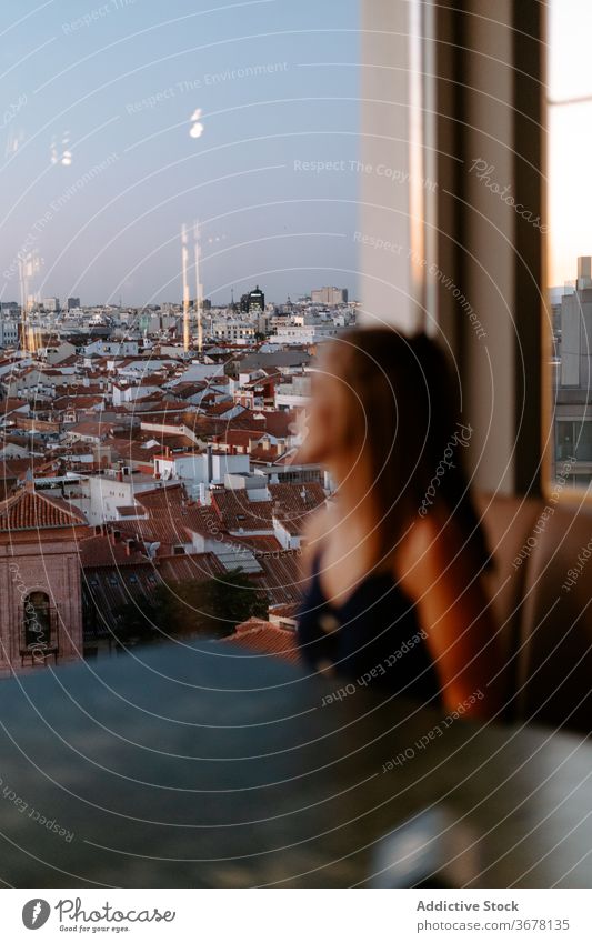 Junge Frau genießt das Stadtbild vom Café aus Dachterrasse Großstadt Fenster Abend Madrid Sonnenuntergang gemütlich urban Spanien Glaswand Komfort