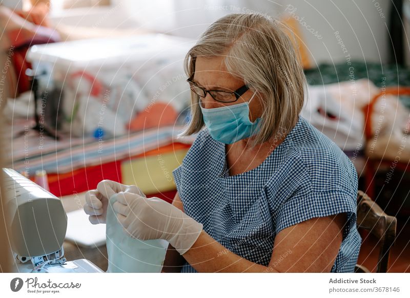 Näherin hält Stoff mit Schere Coronavirus Mundschutz nähen Gewebe Frau Kunstgewerbler COVID handgefertigt Pandemie behüten selbstgemacht verhindern COVID19