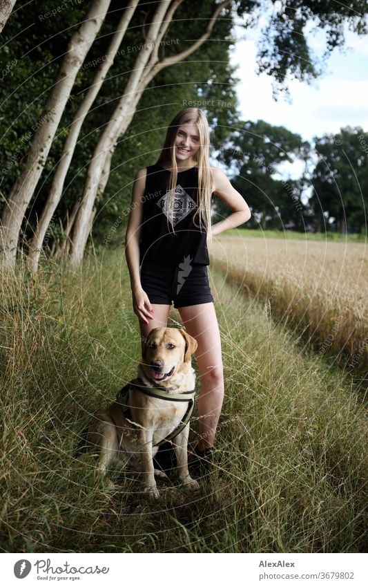 Portrait einer jungen Frau in der Natur vor einem Wald am Feldrand mit blondem Labrador Reinheit Glück Schönes Wetter Ausflug Erwartung Sonnenlicht Nahaufnahme