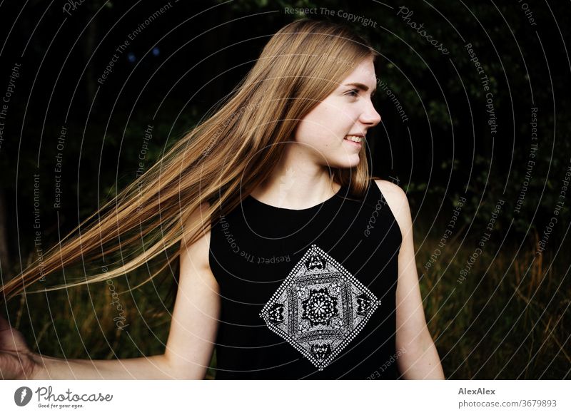 Seitliches Portrait einer jungen Frau in der Natur vor einem Wald, die ihre Haare ausbreitet Reinheit Glück Schönes Wetter Ausflug Erwartung Sonnenlicht