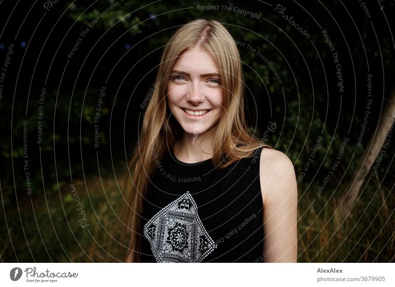 Portrait einer jungen Frau in der Natur vor einem Wald Reinheit Glück Schönes Wetter Ausflug Erwartung Sonnenlicht Nahaufnahme Tag Blick in die Kamera Farbfoto