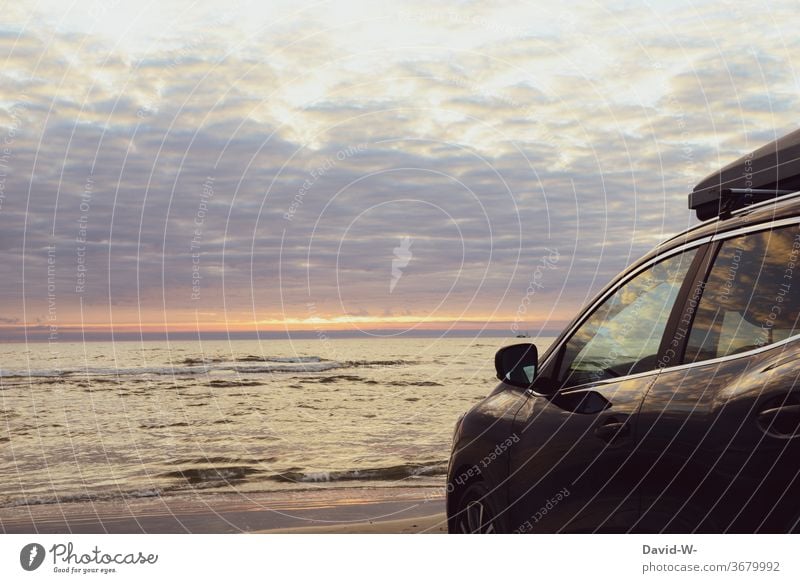 Autostrand - Auto mit Dachbox steht bei Sonnenuntergang am Meer Strand Urlauber Himmel Wasser Ozean Urlaubsstimmung parken Sonnenlicht wunderschön spiegelung