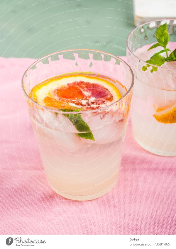 Sommerliches geeistes Zitrusgetränk mit Minze auf rosa Serviette trinken Zitrusfrüchte Wasser Cocktail Limonade aufgegossen Entzug Blutorange Kalk Frucht Saft