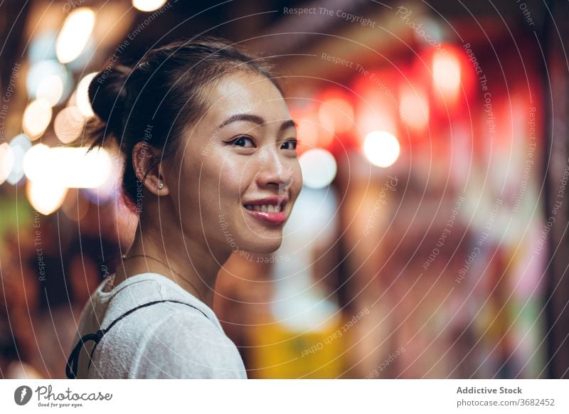 Fröhliche ethnische Frau in der Nacht Stadt Glück Lächeln Großstadt Straße jung positiv heiter urban froh Freude asiatisch lässig Lifestyle leuchten Abend