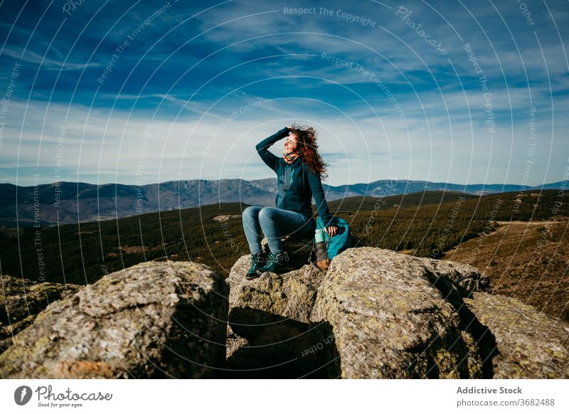 Glückliche weibliche Reisende in den Bergen Frau Berge u. Gebirge reisen Rucksack sitzen Lächeln Landschaft puerto de la morcuera Spanien Stein heiter Urlaub